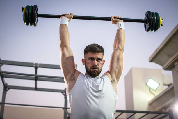 istock Muscular young man lifting barbells in public gym. 919564384