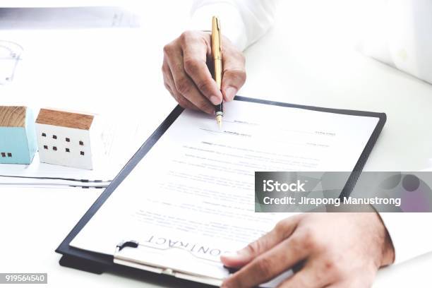 Businessmen Are Checking The Contract To Use The Right Pen Signed Building Approval With Blueprint And House Model On The Table Stock Photo - Download Image Now