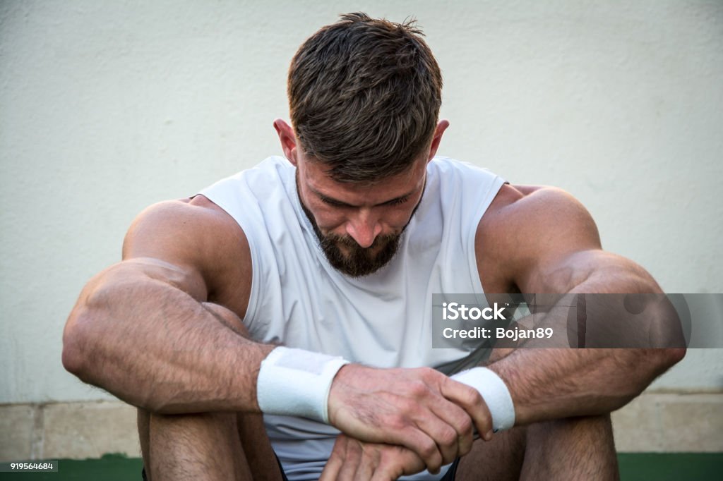 Tired athletic man looking down after intensive fitness workout. Men Stock Photo