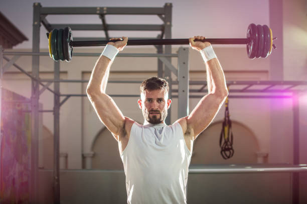 istock Strong handsome man lifting weights at outdoor gym. 919564686