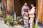 伝統的なドレス京都で木製の壁への入り口の前に立ってと 2 つの美しい女性のビュー