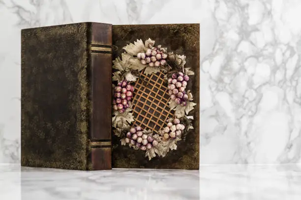 Wooden box with grapes and leaves figures on white marble table