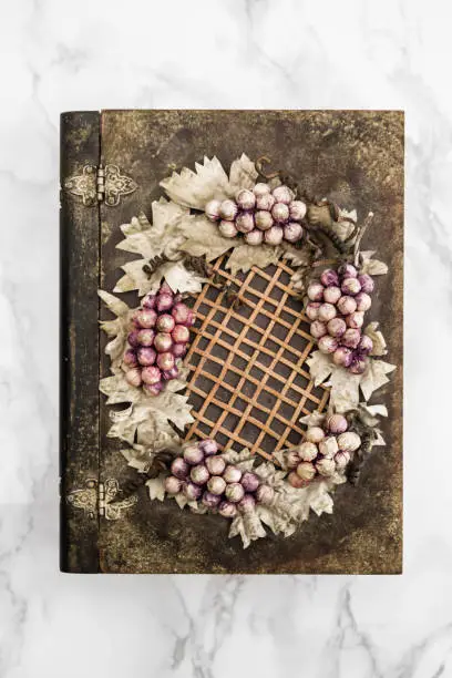 Wooden box with grapes and leaves figures on white marble table