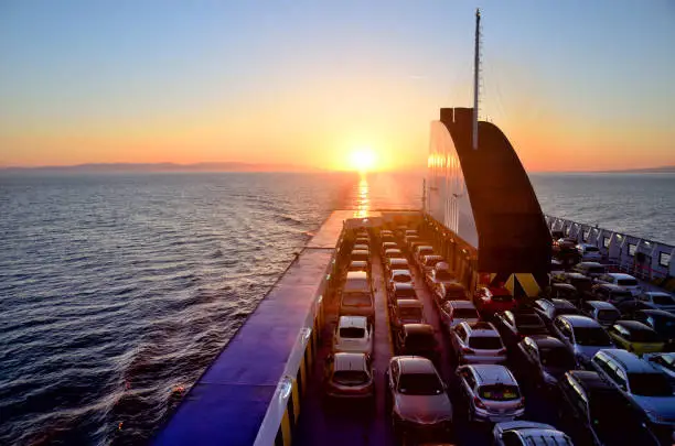 Ferry with cars on the sea at sunset
