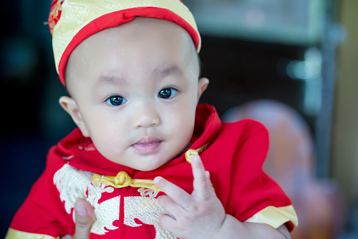 Focus cute baby boy wear red and gold chinese suit on chinese new year day. fancy clothes for baby and child. pretty infant. Asian baby boy.image for background, wallpaper, copy space and illustration