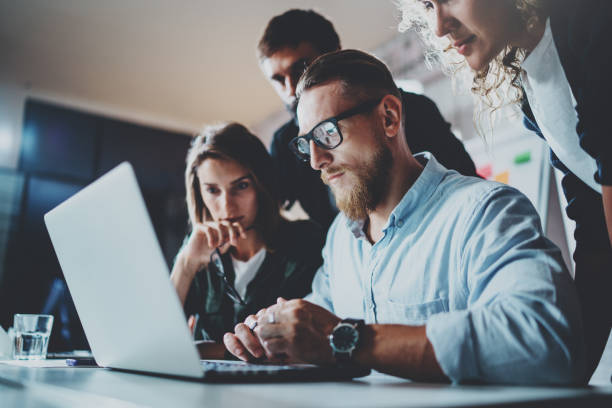istock Teamwork brainstorming process.Young man working together with partners in modern office loft.Business startup concept.Blurred background.Flares. 919641572