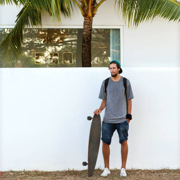 istock guy on skateboard at sunset near white wall and palm 919645380