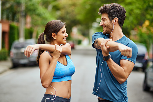 Shot of a sporty young couple stretching while exercising together outdoors