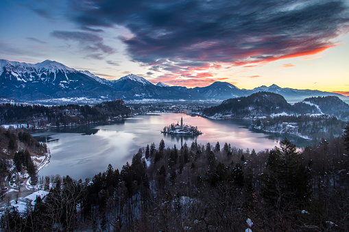 View of Lake Bled in Slovenia from the viewpoint on the hill above the town. In the distance you can see the high rocky mountains of the Julian Alps.