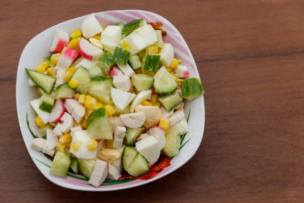 istock Salad with crab sticks, sweet corn, cucumber and eggs on wooden table 919725088