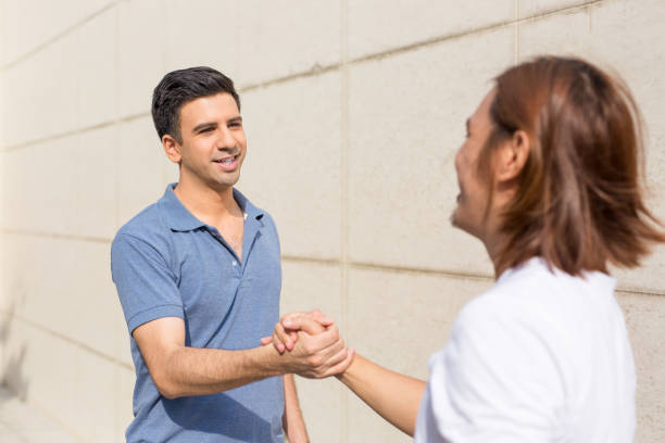 istock Two Happy Male Friends Shaking Hands Outside 919732540