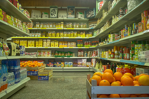 Interior of a supermarket with view of shelves full of goods and groceries on display.