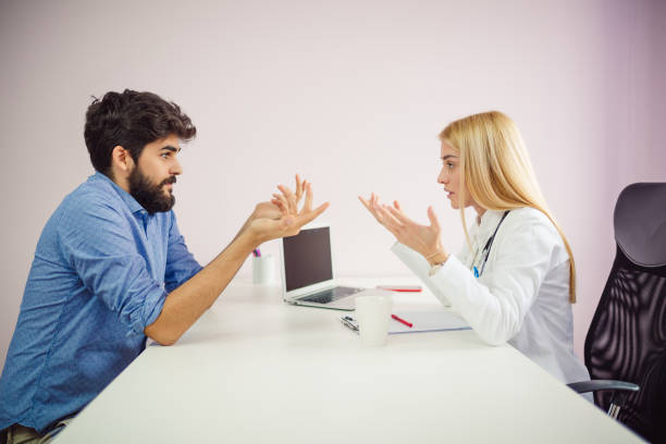 Cheerful young doctor listening to a patient in the office. Doctor talking with patient. stock photo