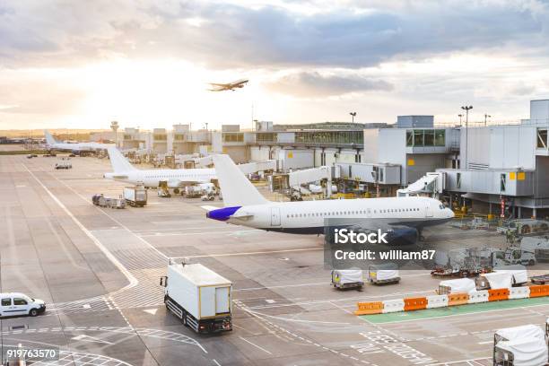 Busy Airport View With Airplanes And Service Vehicles At Sunset Stock Photo - Download Image Now