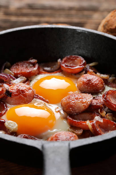 istock Fried eggs with sausage and onion on frying pan 919768208
