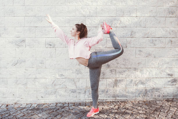 istock Woman Balancing on One Leg and Stretching Body 919768370