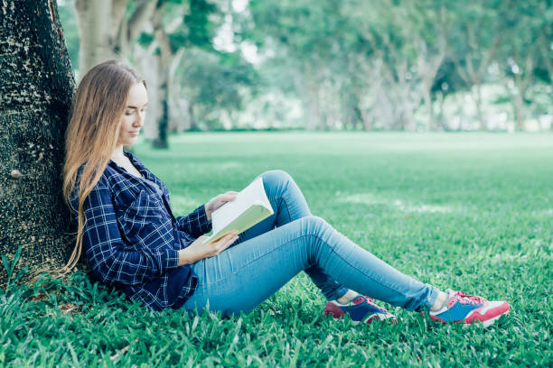 istock Calm young student reading book in tranquil park 919769094