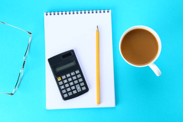 istock Top view image of open notebook with blank pages and coffee on blue background, ready for adding or mock up. Still life, business, office supplies or education concept. 919785594