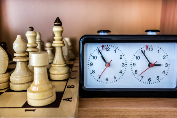 Chess background with a wooden board and clock Chess background with a wooden board, chess pieces and clock close-up for all ages. chess timer stock pictures, royalty-free photos & images