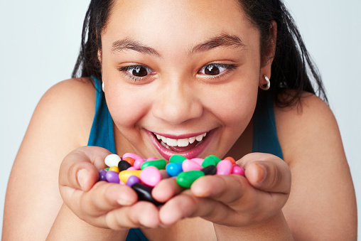 Studio shot of a cute young girl holding a handful of colorful jelly beans