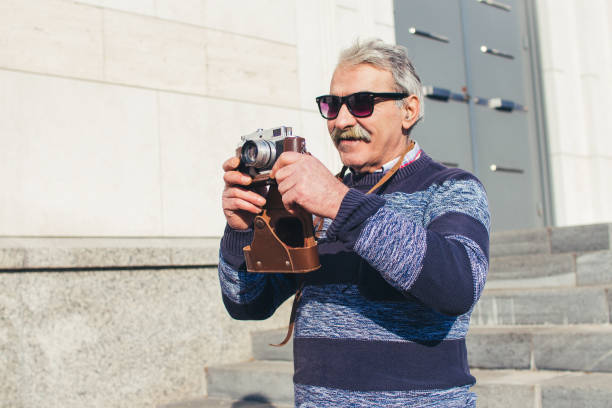 istock Senior man photographing with retro camera. 919803650