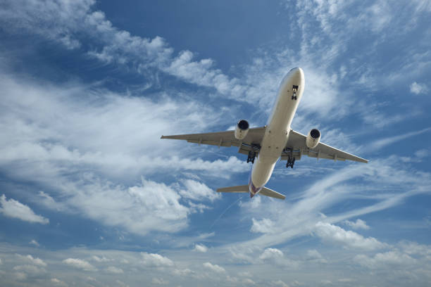 istock airplane flying under clouds and blue sky 919806738