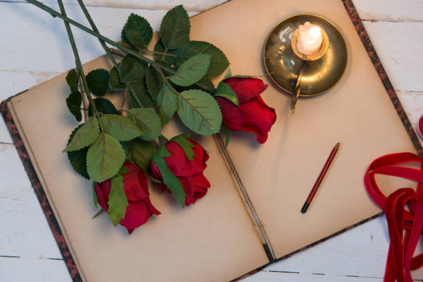istock concept romantic, old notebook, three  roses and small candle 919815884