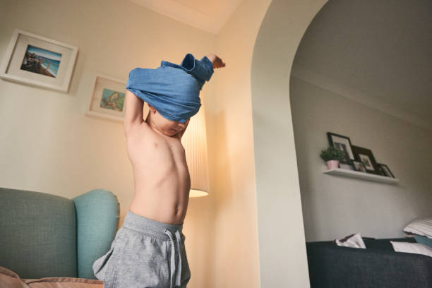 niño quitándose su camiseta - undressing fotografías e imágenes de stock