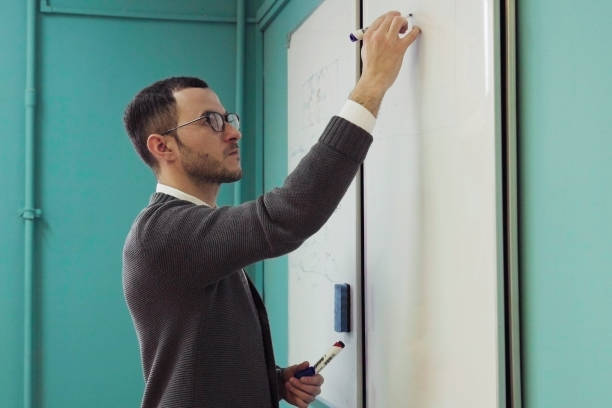 istock Young male lecturer writes on whiteboard in classroom 919830418