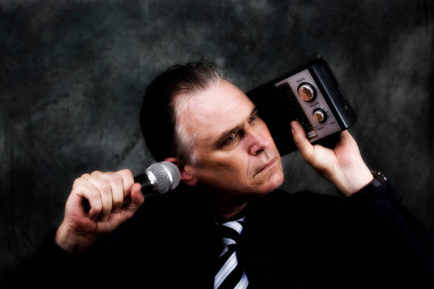 istock Man listens to an old fashioned radio while holding a microphone 919854808