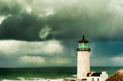 Heavy clouds from stormy skies hang over the ocean while the ever present North Head Lighthouse stands in the foreground.