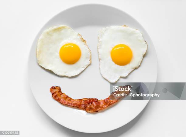 Smiling And Positive Face Made From Fried Eggs And Bacon On Plate Stock Photo - Download Image Now