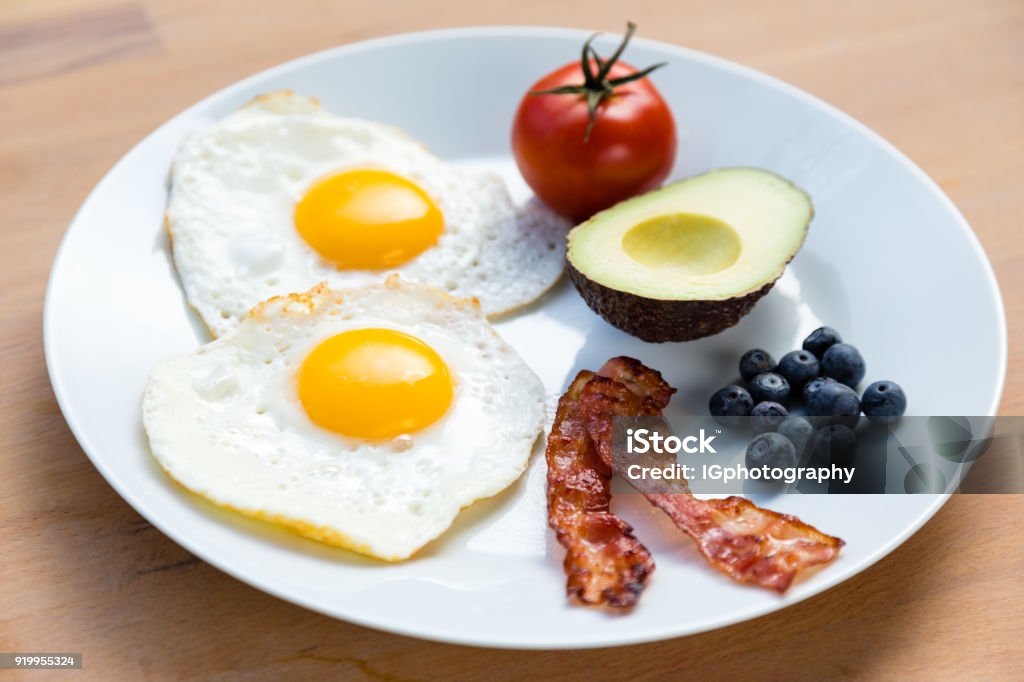 Healthy Breakfast for Weight Loss and Vitality Healthy breakfast on plate consisting of fried eggs and bacon, half an avocado, a tomato and a handful of antioxidant rich blueberries. Animal Egg Stock Photo