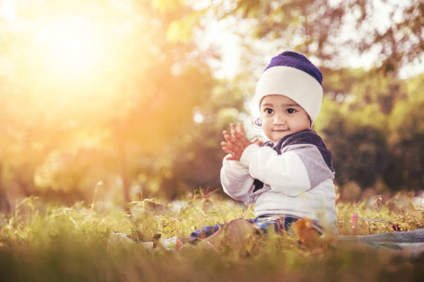Indian baby girl playing with alphabet and abacus toy at the park. She is Sitting and on the grass. colorful Alphabet blocks and abacus lying around her. one person, horizontal composition with copy space and selective focus.