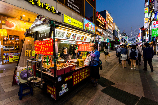 Suwon, South Korea - June 14, 2017: Adult man buying fast food at main street in Suwon. Street food is very popular in Korea. You can buy kimbap, teokbokki, bibimbap, kimchi.