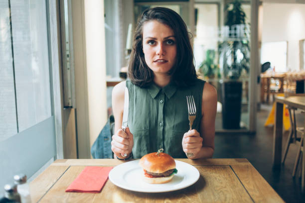 istock Beautiful woman eating burger in restaurant 919963982