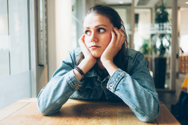 istock Pensive young woman sitting in cafe alone 919963988