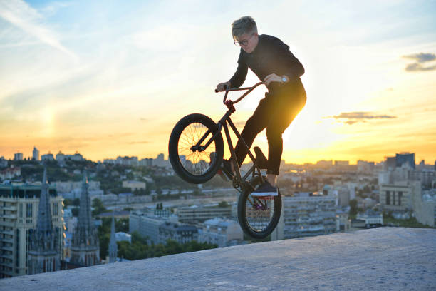 silhouette of a man doing an jump with a bmx bike against sunshine sky. - bmx cycling bicycle street jumping imagens e fotografias de stock