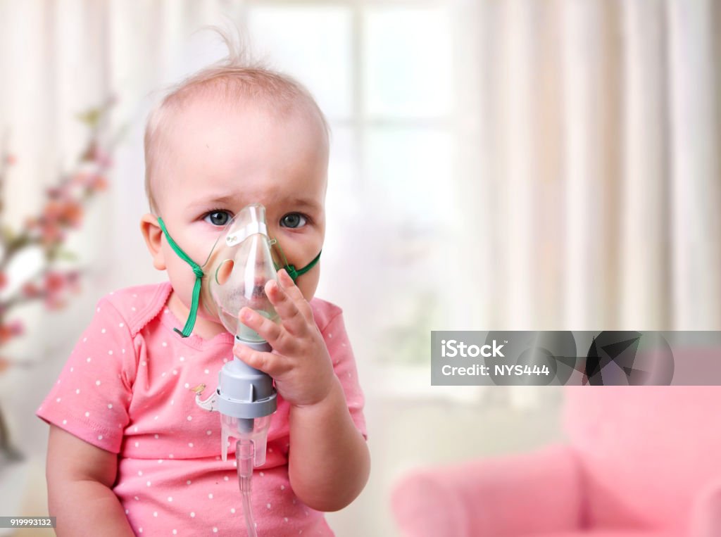 Baby inhalation,child with mask on face. Baby girl making inhalation with mask on her face.Inhaling child. Baby - Human Age Stock Photo