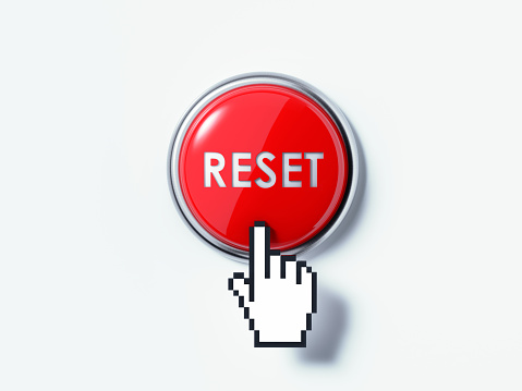 Hand shaped computer cursor is clicking on a red computer button on white reflective surface. Reset writes on the push button. Horizontal composition with copy space and clipping path.