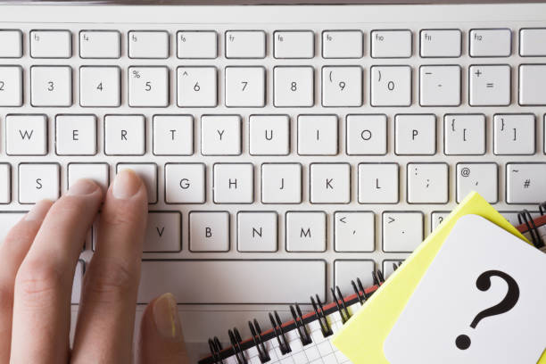 femme à l’aide d’ordinateur portable à la maison ou au bureau. de la main les doigts tapant sur un clavier et à la recherche d’informations. point d’interrogation. problème et solution concept. - faq connection computer keyboard learning photos et images de collection