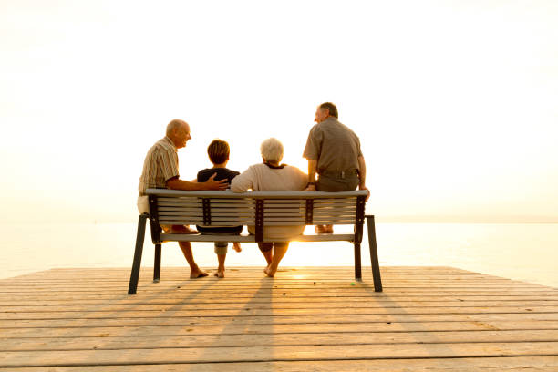 istock Diverse Active Seniors - back view four seniors sitting at lake in bright sunset 920014542
