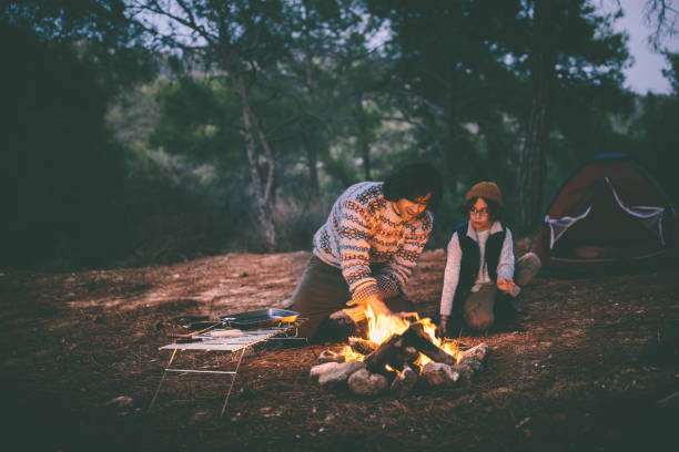 istock Father and son camping in the woods and lighting campfire 920017138