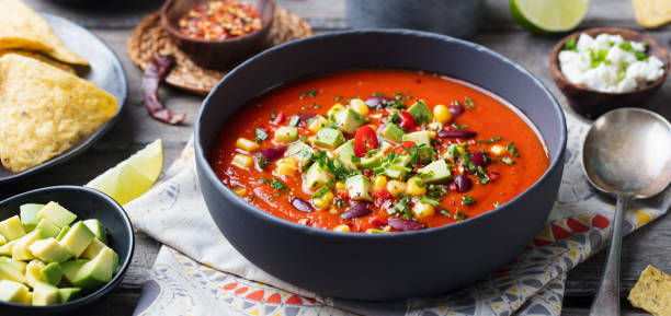 Mexican tomato, bean, bell pepper soup in black bowl.