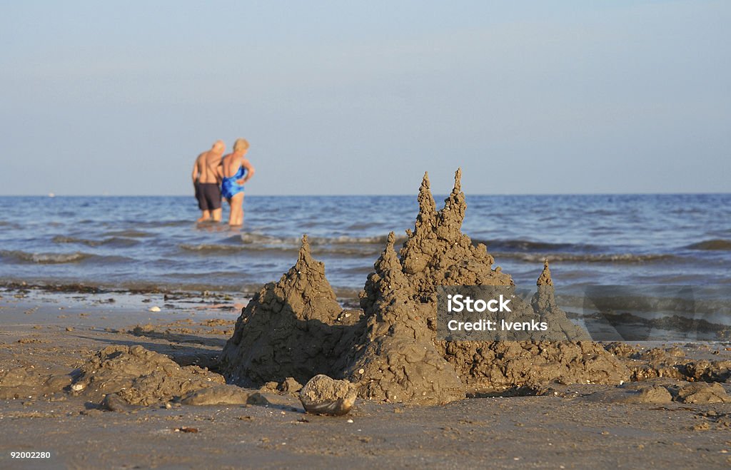 Châteaux de sable et de couple senior dans la mer - Photo de Château de sable - Structure libre de droits