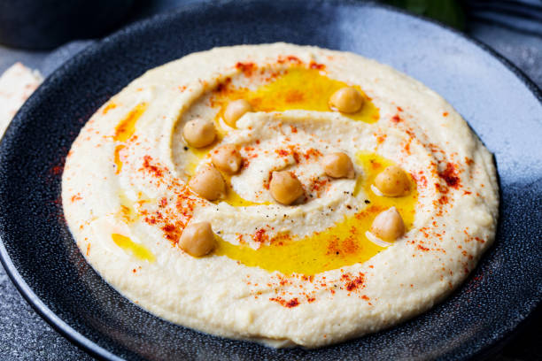 istock Hummus, chickpea dip, with spices and pita, flat bread in a black plate on grey stone background. Top view. 920027208