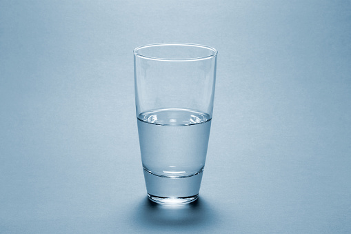 Half full water glass over blue background