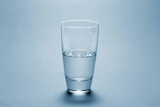 Photo of Half full water glass over blue background