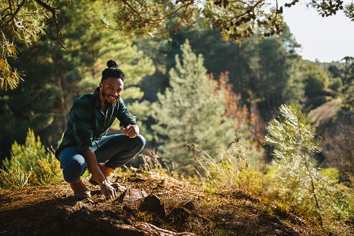 Portrait of young african american man relaxing under tree on mountain hiking adventure in summer