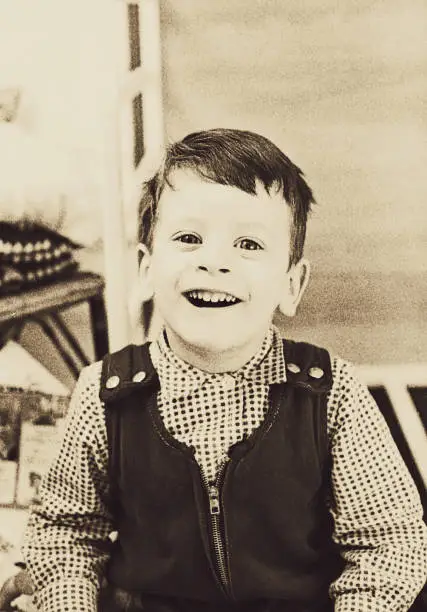 vintage black and white toned image of a cute kid laughing and smiling at camera